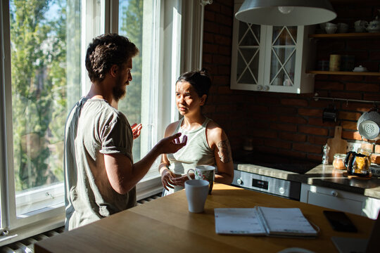 Couple discussing finances over coffee in sunlit kitchen