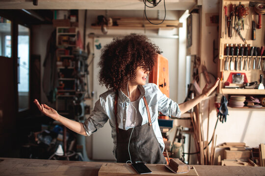 Female carpenter listening to music in woodshop