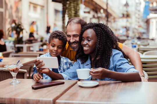 Parents and son taking a selfie at an outdoor cafe