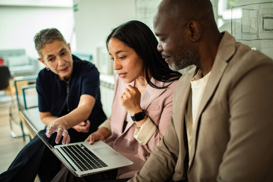 Coworkers collaborating on a laptop in modern office