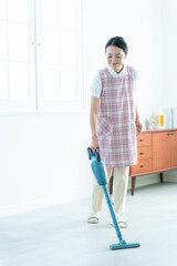 掃除機をかける家事代行の女性 © taka