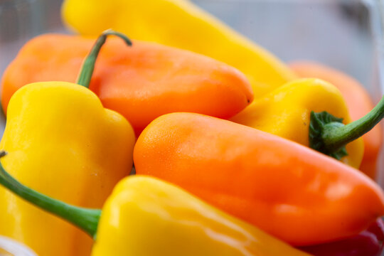 Close up of vibrant fresh orange and yellow mini sweet bell peppers.A high-quality close-up macro photograph showcasing a bright colorful heap of fresh, organic mini sweet bell peppers (capsicum). 