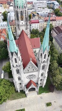 Aerial footage from St. Paul's Church in Munich, Germany. Cinematic drone shot revealing the neo-gothic architecture, green spires, and urban city skyline.