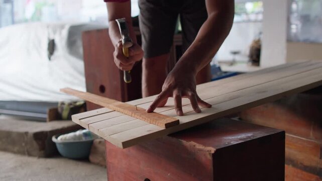 Carpenter hammering nails into wooden planks during a woodworking project, showcasing construction, carpentry skills, and craftsmanship.