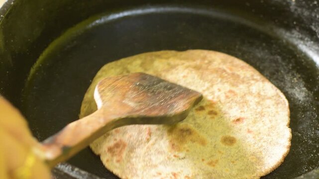 Woman Preparing Fresh Multigrain Roti on a Traditional Cast Iron Tawa