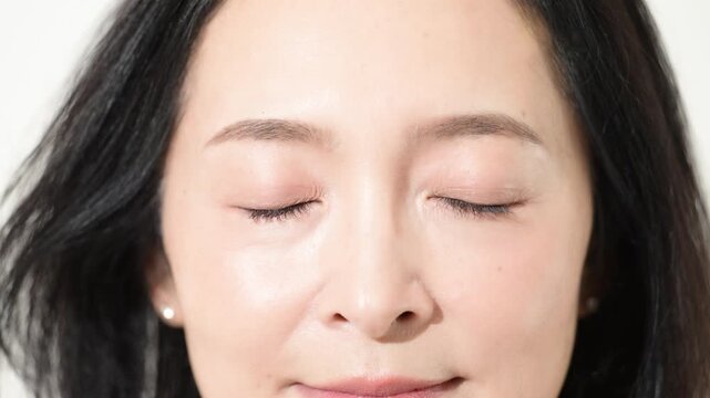 ミドル女性の目元、目尻のしわや年齢肌、アイケアとエイジングケアの美容イメージ　ゆっくり目をあけるクローズアップのスロー動画	