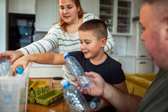 Family recycling plastic bottles together in home kitchen