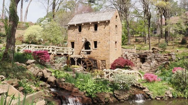 Stone water mill with wooden bridge and waterfall.
