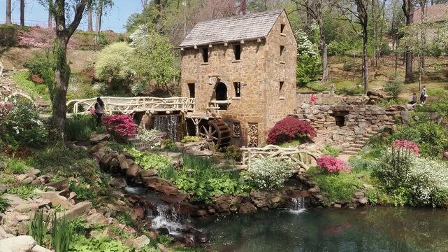 Stone water mill with wooden bridge and stream.