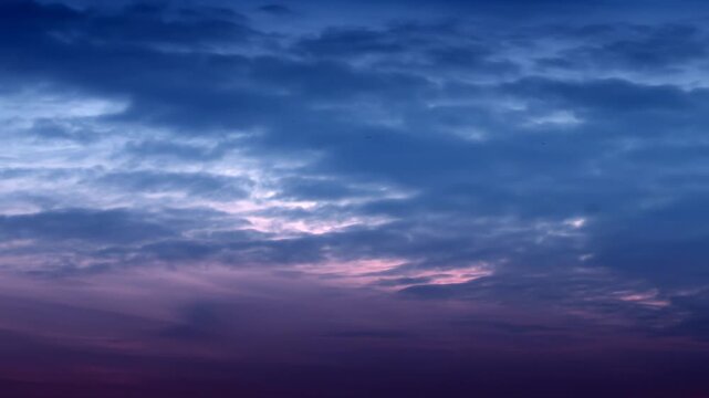 Time-lapse of dramatic twilight sky with moving clouds in deep blue and purple hues during blue hour