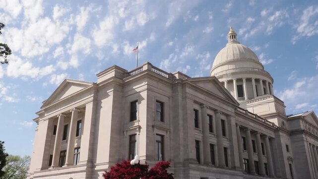 Neoclassical state capitol building with dome and flag.