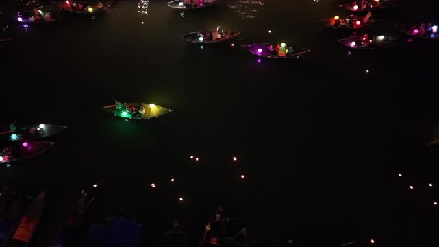 Boats adorned with vibrant lanterns float on the water, creating a magical atmosphere during a festive night in Hoi An, Vietnam