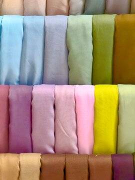 Colorful hijab fabrics neatly arranged on display, showcasing variety of pastel and vibrant colors for fashion and textile background use