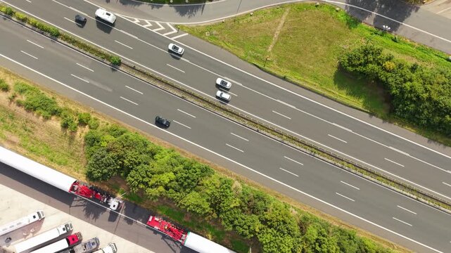 Aerial perspective of a busy highway featuring various vehicles moving in both directions, bordered by lush greenery and roadside structures