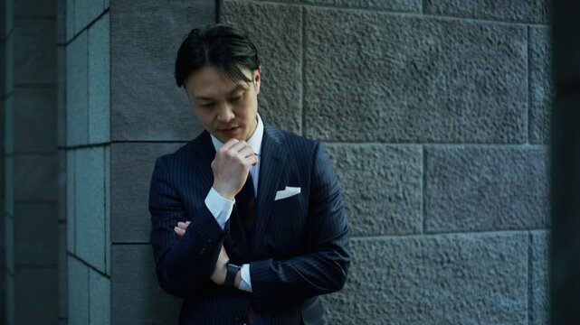 Businessman thinking with a hand on his chin in a dim passage