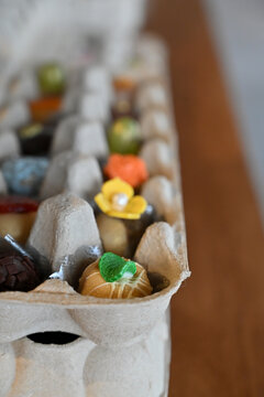 gourmet sweets and brigadeiros arranged in recycled egg cartons on wooden table, creative rustic brazilian event party favors display, wide horizontal shot