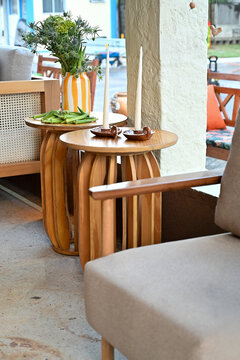 table and chairs, wooden side tables with taper candles and vase arrangement, outdoor patio lounge decor, modern hospitality furniture concept