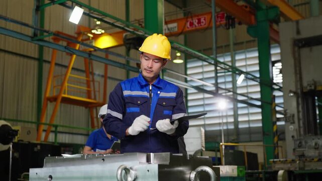 Asian factory engineer reviewing industrial machine parts using tablet for quality control inspection at manufacturing plant