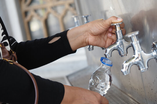Woman filling a water bottle at a water fountain during the day