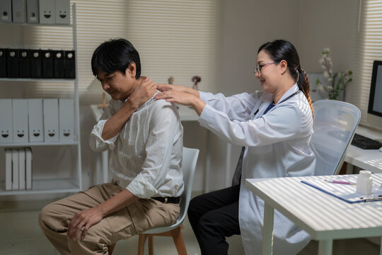 Asian Female Doctor Examining Senior Patient Suffering from Severe Lower Back Pain