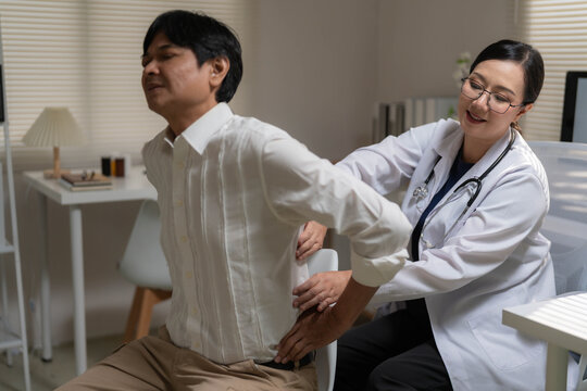 Asian Female Doctor Examining Senior Patient Suffering from Severe Lower Back Pain