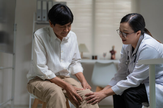 Asian Female Doctor Examining Patient's Knee Pain during Clinic Consultation