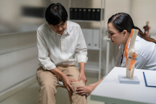 Asian Female Doctor Examining Patient's Knee Pain during Clinic Consultation