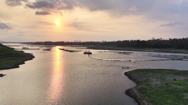 The warm sunlight creates a brilliant reflection on the water surface under a cloudy sky