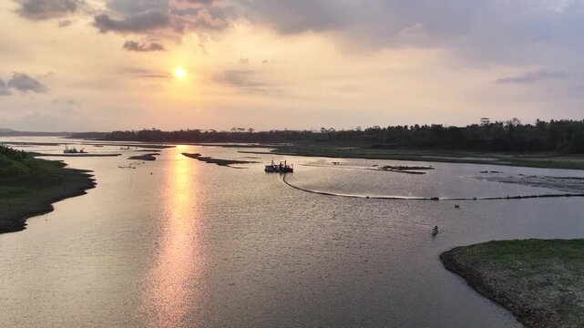 The warm sunlight creates a brilliant reflection on the water surface under a cloudy sky
