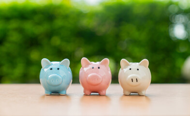 Three piggy banks on table with green nature background, Save money for prepare retirement concept.