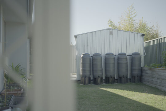 water tank, rainwater harvesting, sustainability, garden shed, water storage, conservation, eco-friendly setup for domestic water management in a modern suburban backyard garden.