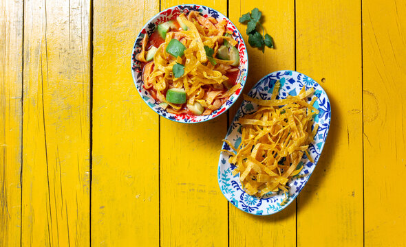 Fried tortilla soup with fresh corn and vibrant toppings served on colorful pottery