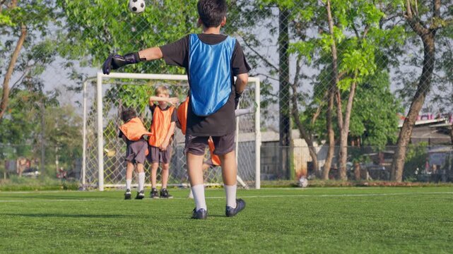 Rear view of young boy playing football on outdoor soccer field. 