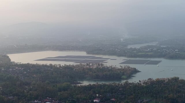 Hazy morning blankets the tranquil waterway. Distant hills fade in foggy embrace at Sukowilangun, Malang