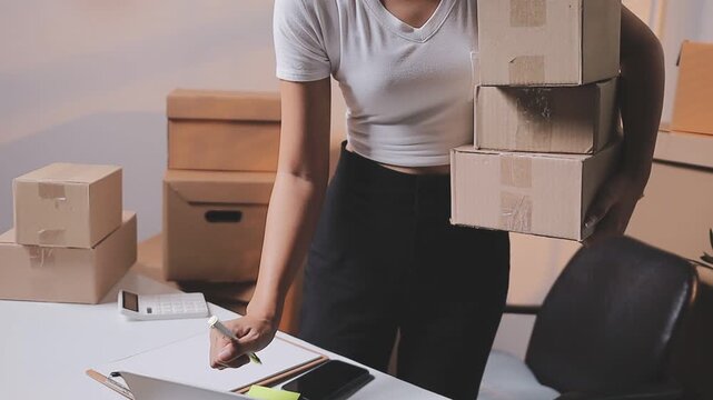 Close up with Start up small business, SME female owner using laptop checking order online to prepare to pack a box of goods for sale to customers, sme business idea.