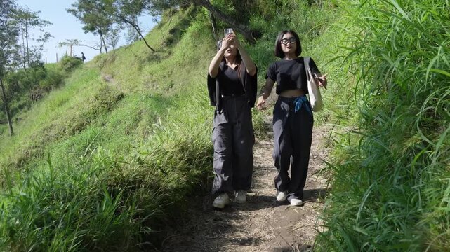 Two Gen Z Women Hiking and Taking Selfies on a Mountain Trail Near Mount Merapi