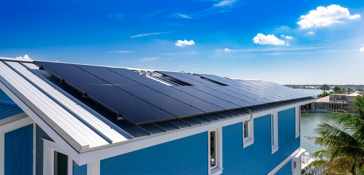 Panoramic view of rooftop solar panel array installed on standing seam metal roof of coastal house in USA