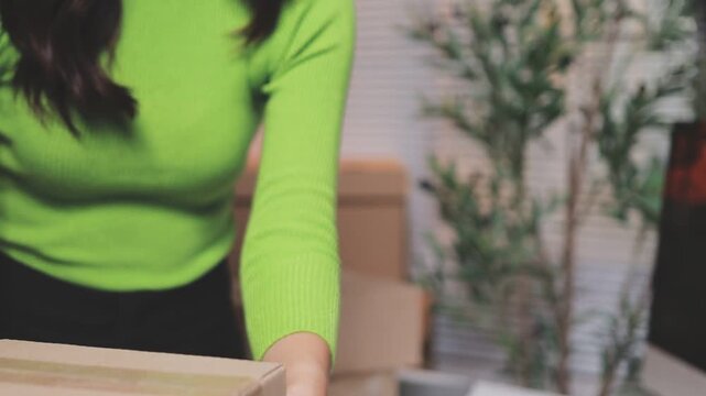 Close up with Start up small business, SME female owner using laptop checking order online to prepare to pack a box of goods for sale to customers, sme business idea.