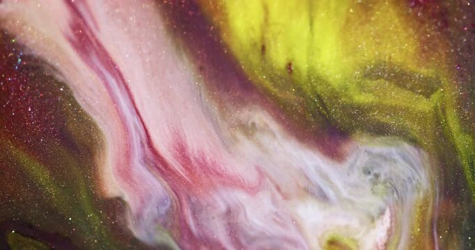 Glitter paint. Fluid art. Defocused yellow pink purple color shiny pigment blend sparkling texture spilling on abstract background.