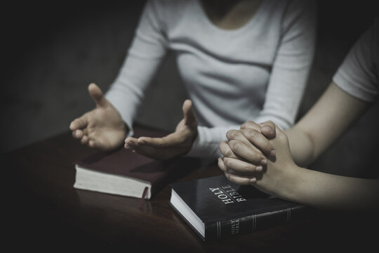 Holy Bible and Wooden Cross with Hands in Prayer for Christian Faith, Devotion, Hope and Religious Worship.