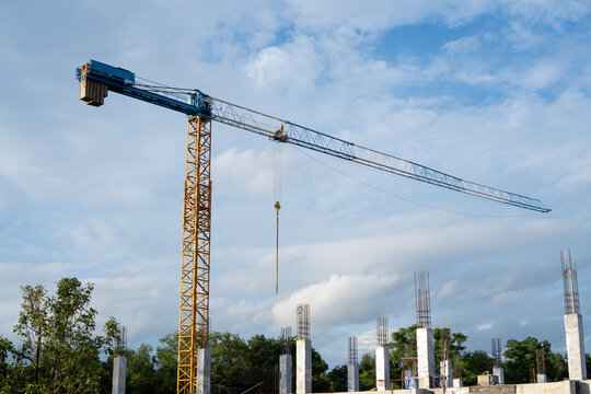 Tall construction crane stands proudly at outdoor site under blue sky, representing optimistic growth, heavy building equipment, machinery, industrial structure, ambitious development project