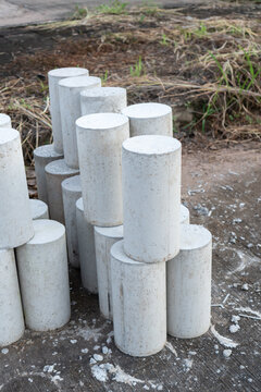 Concrete cylinder sample test specimen standing on construction site ground, showing raw material strength with quiet calm industrial mood for civil engineering project quality inspection work