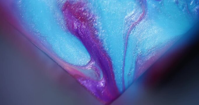Glitter paint. Fluid art. Defocused purple pink blue colorful shiny triangle blend sparkling texture spilling on abstract background.