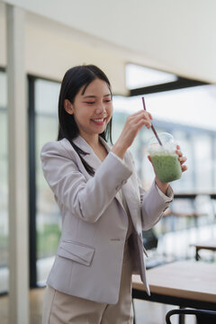Young asian businesswoman enjoying iced matcha latte drink