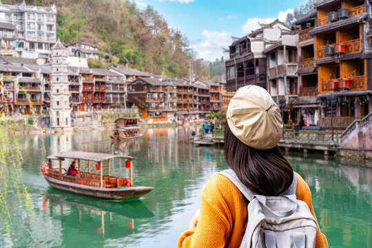 Young woman traveler looking at the view of Fenghuang Ancient Town, the famous tourist destination in Hunan Province, China