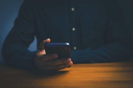 Man using a smartphone on a wooden table. Concept of technological communication for online business, internet connectivity, chat, social media, and modern mobile networks.