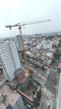 High-angle view of a tower crane operating over a building foundation pit in an urban area