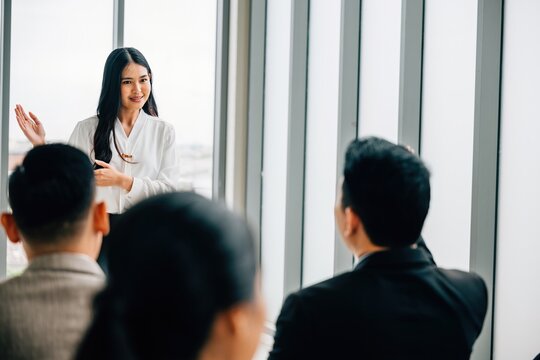 In an office setting, a confident woman team leader takes charge of a meeting, presenting a project. She also serves as a speaker and coach, discussing finance, plan, and strategy.