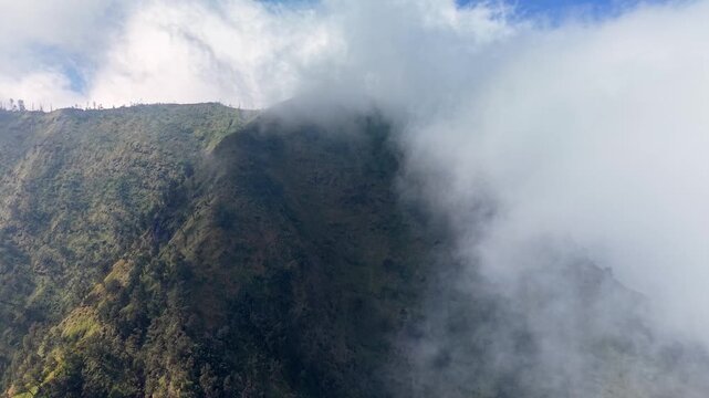 Aerial view of mist shrouded volcanic ridge and rolling clouds at Wonokerto Sukapura, Java, Indonesia.