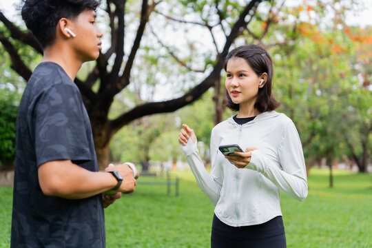 Asian sporty man and woman talking together in public park